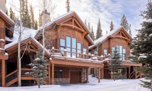 Luxury ski-in/ski-out chalet at Big Sky Resort with timber architecture and snow-covered roofline surrounded by pine trees.