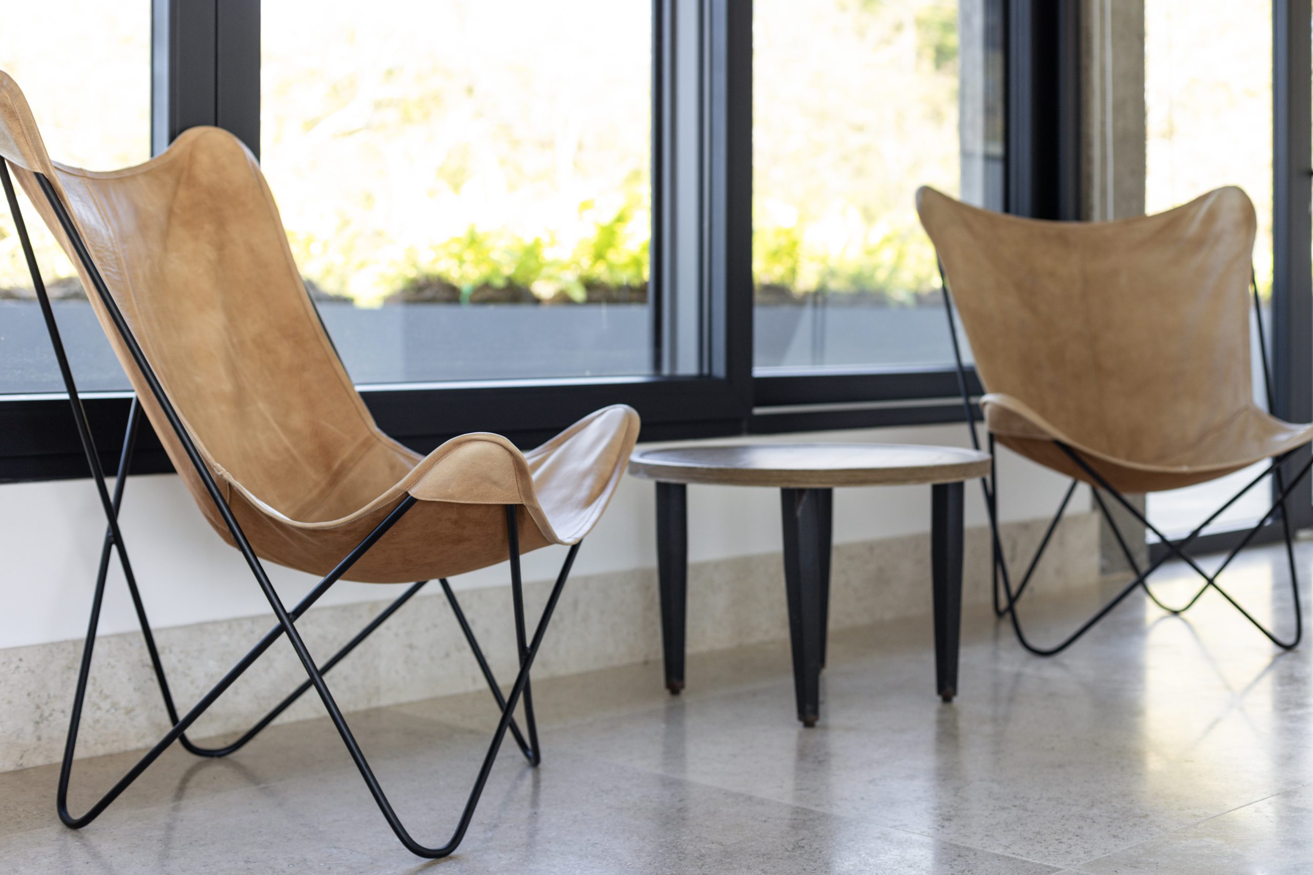 Modern seating area with gray armchairs, and glass doors opening to a pool view.