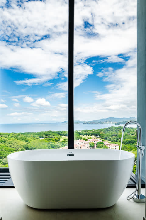 Luxury bathtub with floor-to-ceiling windows offering stunning ocean views at the Reserva Conchal penthouse in Costa Rica.