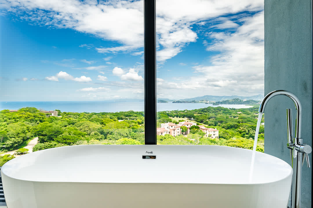 Luxury bathtub with floor-to-ceiling windows offering stunning ocean views at the Reserva Conchal penthouse in Costa Rica.