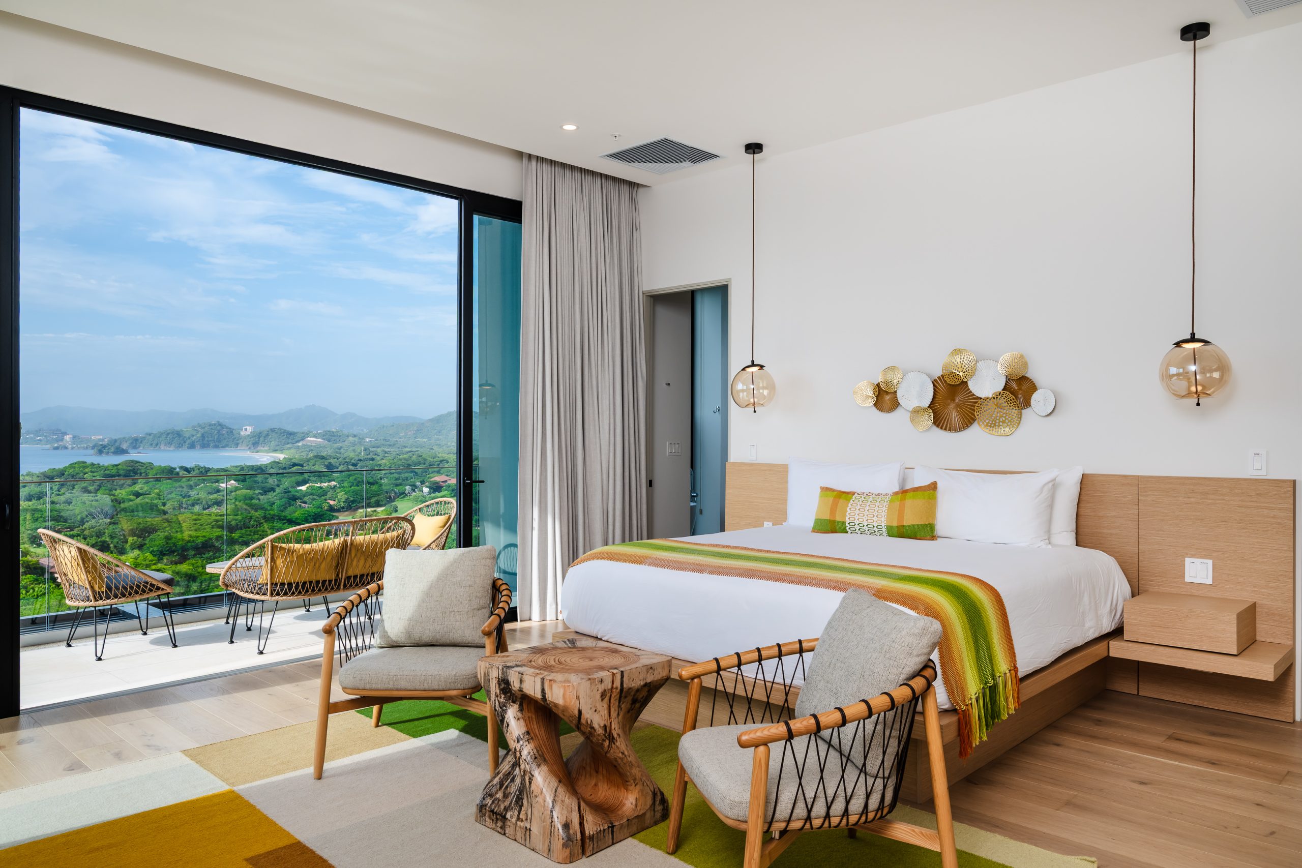 Luxury bedroom with floor-to-ceiling windows overlooking lush greenery and ocean views at the Reserva Conchal penthouse in Costa Rica