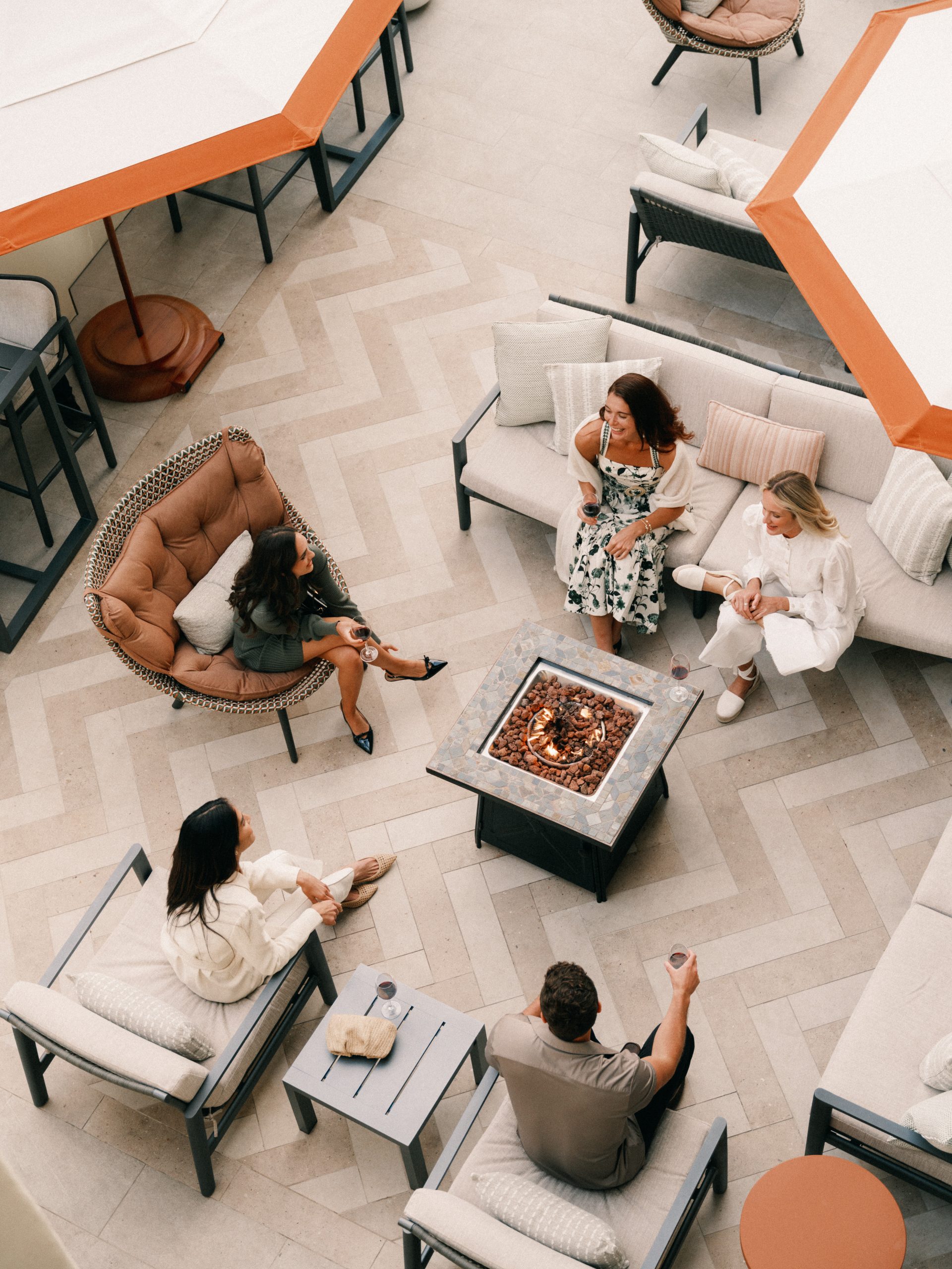 group of friends relaxing around a fire pit at a luxury outdoor lounge with modern furniture and cocktails at terranea resort