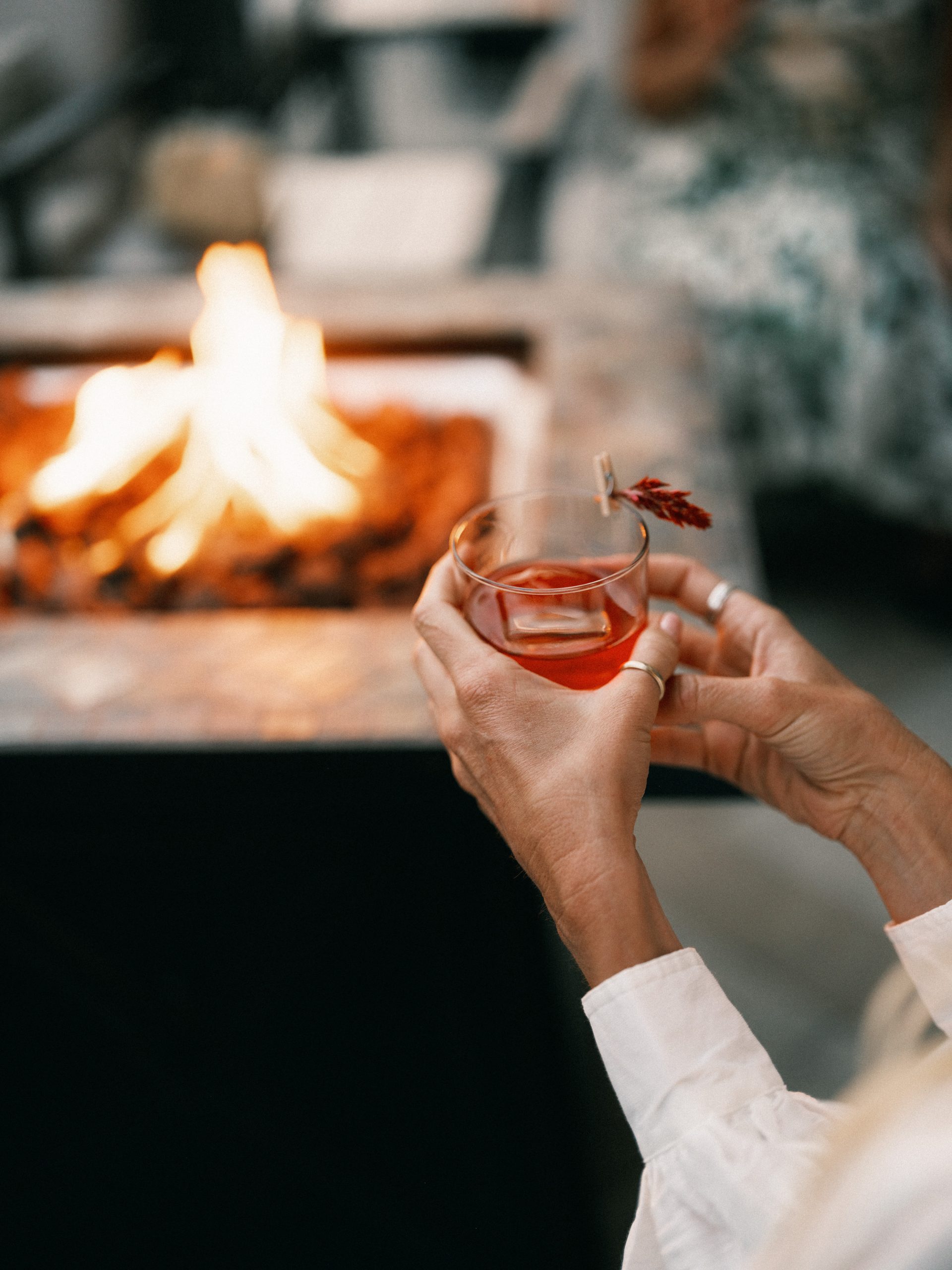 Hand holding a cocktail by a fire pit at Terranea Resort spa lounge.