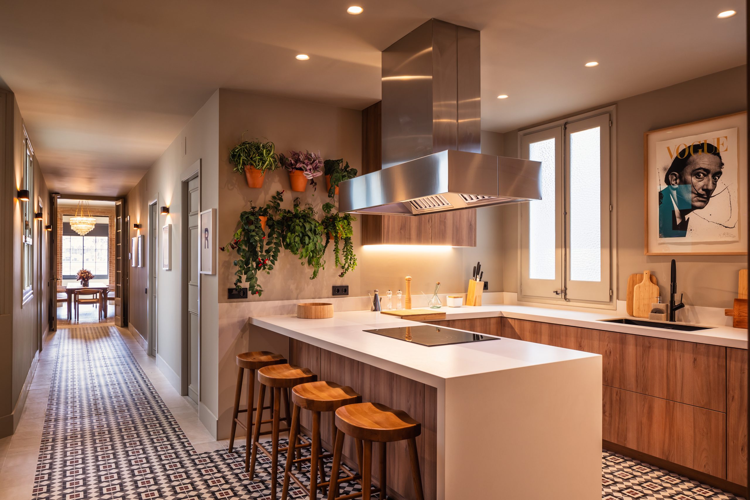 Modern Barcelona kitchen with wood cabinetry, hanging plants, and stylish breakfast bar.