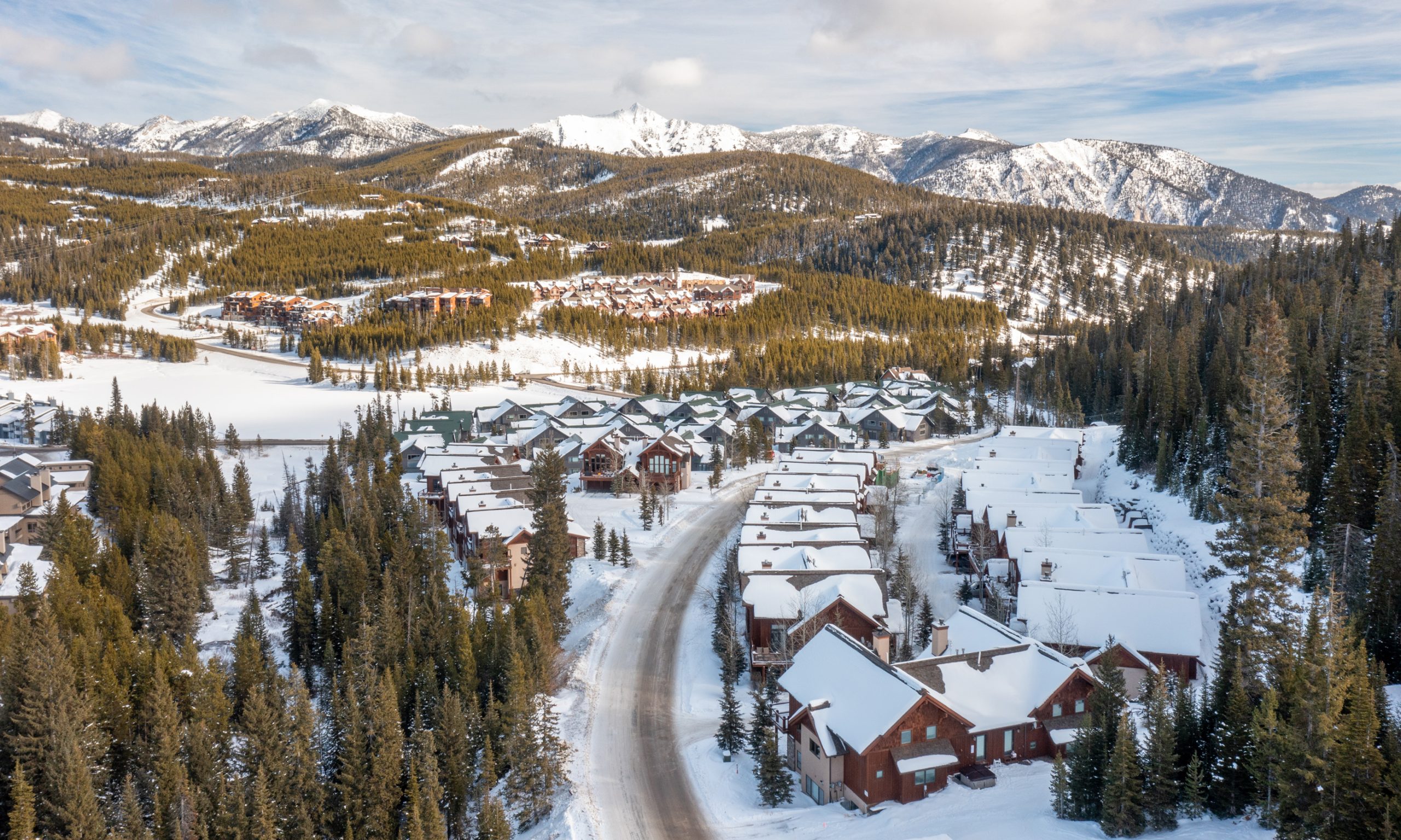 Luxury mountain homes surrounded by pine trees and fresh snow at Big Sky Resort.