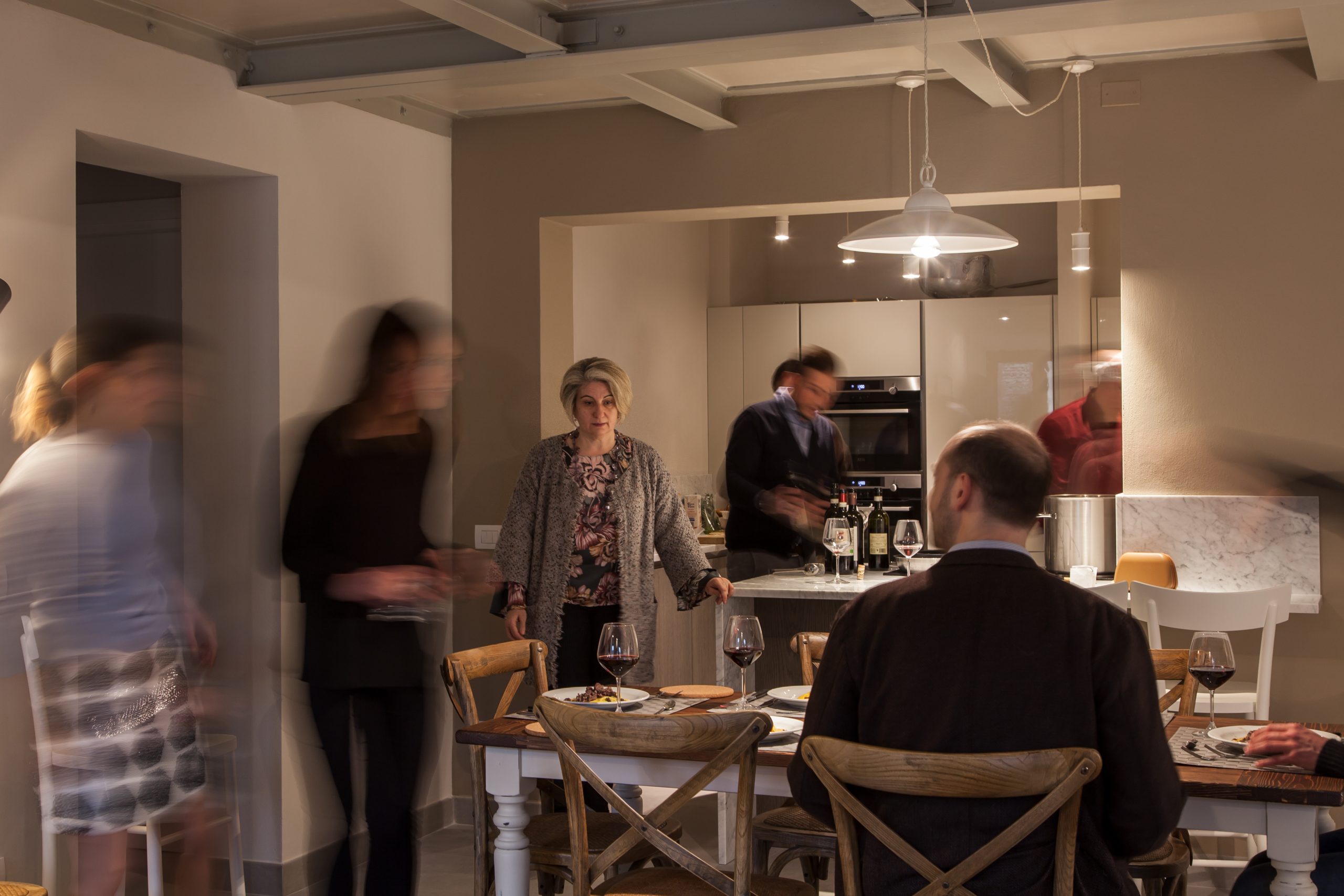 Elegant dinner party in a luxury penthouse kitchen with guests enjoying fine wine, gourmet food, and warm conversation under cozy lighting in siena, italy