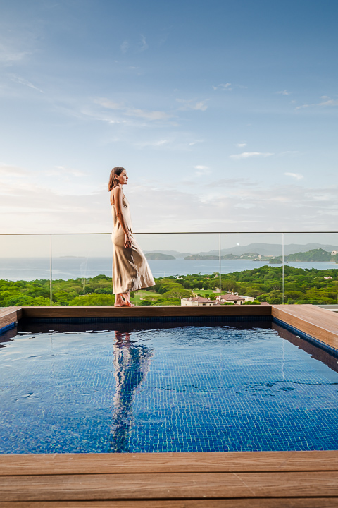 Woman standing by private infinity pool with panoramic ocean and jungle views at Reserva Conchal.