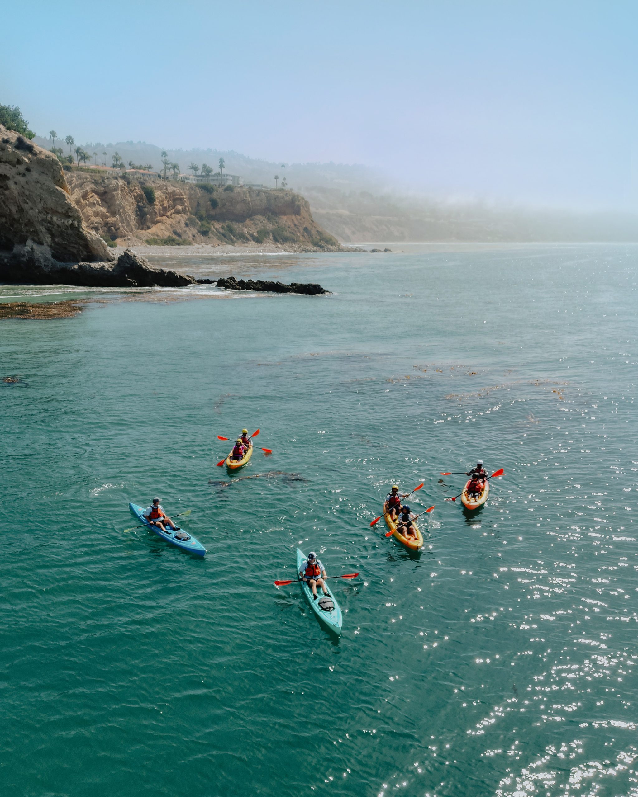 Group kayaking along the rocky coastline near Terranea Resort in Rancho Palos Verdes, California.